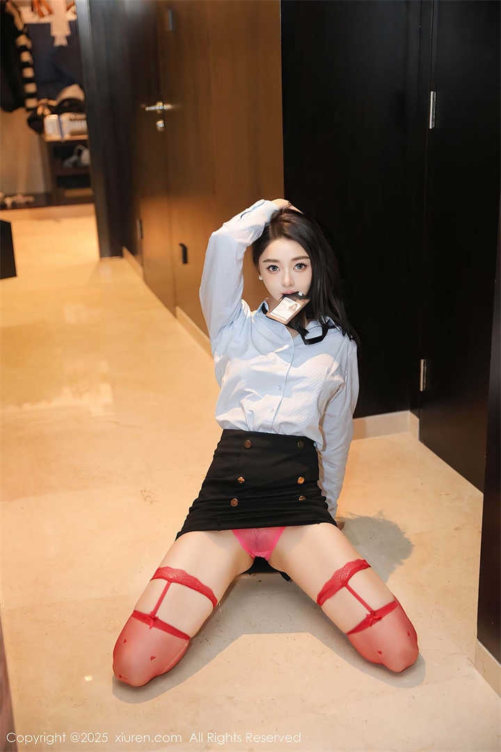 模特Candy糖糖身穿白衬衫、黑短裙和爱心图案的红色丝袜，扮演性感OL坐在办公室里。