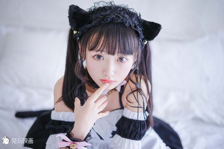 一位扎着双马尾、头戴猫耳的可爱Coser，身穿黑白相间的女仆装，扮演“女仆喵”的角色。