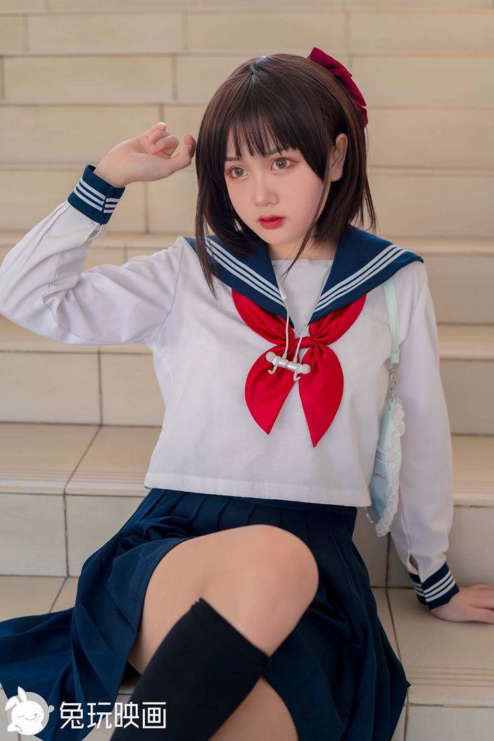 一位留着短发的可爱少女，身穿经典的蓝白色日式水手服JK校服，坐在楼梯上。